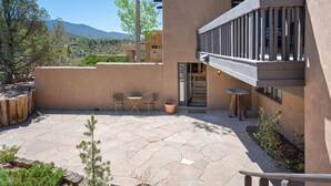A modern building with a patio area featuring stone flooring and two tables with chairs.