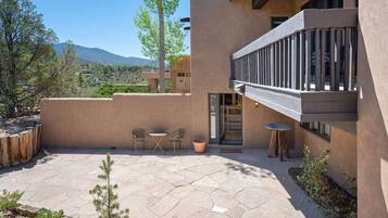 A modern building with a patio area featuring stone flooring and two tables with chairs.