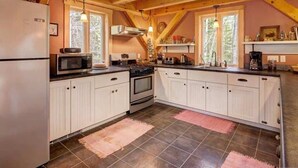 Une cuisine avec des meubles blancs, une cuisinière, un four à micro-ondes et un réfrigérateur.