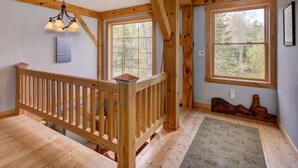 Un intérieur en bois avec un escalier, de grandes fenêtres et un lustre.