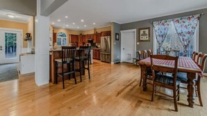 Eine geräumige Küche mit Holzausstattung, einem Esstisch mit Stühlen und einem Kühlschrank.