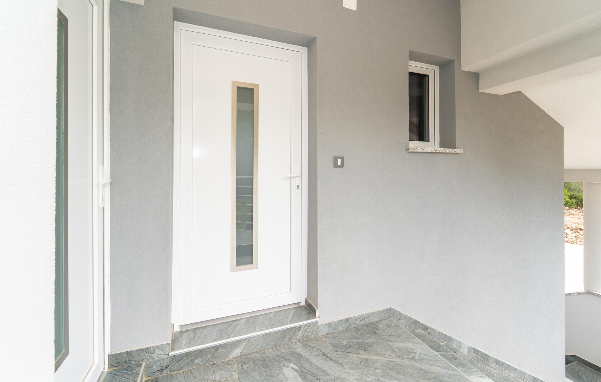 Un passadís amb una porta blanca i una finestra petita.