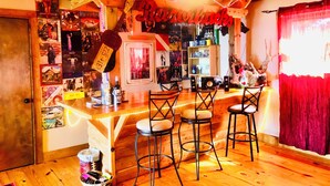 Een bar met houten meubels, een plafondventilator en diverse decoraties, waaronder een bord met de tekst 'Guitarworks'.