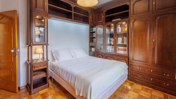 A bedroom with a large bed, wooden wardrobe, and built-in bookshelves. - Holiday Home 'Vez' with Mountain View, Private Garden and Wi-Fi (Arcos de Valdevez)