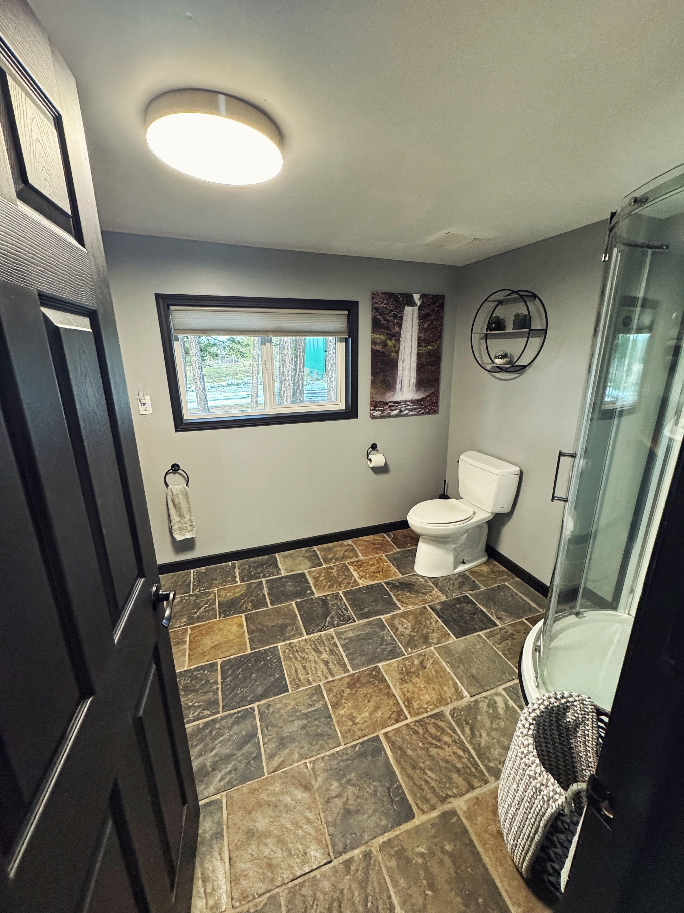 A bathroom with a toilet, a shower, and a window.