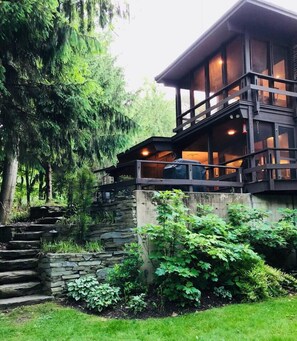 Ein modernes, zweistöckiges Haus mit einer Steintreppe, die zu einer Holzterrasse führt.
