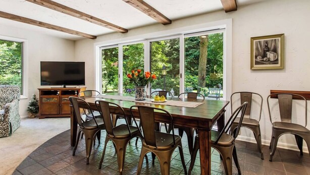 A dining area with a wooden table, chairs, and a television. - Private Pool 5 Minutes From Lake Michigan (South Haven)