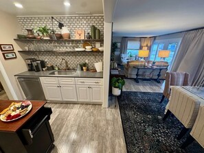 Una cocina moderna con armarios blancos, un lavamanos integrado y varios objetos decorativos en estantes.