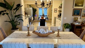 A dining room with a table set for four, a chandelier, and a view into the kitchen. - Hutchins Lake Retreat (Fennville)