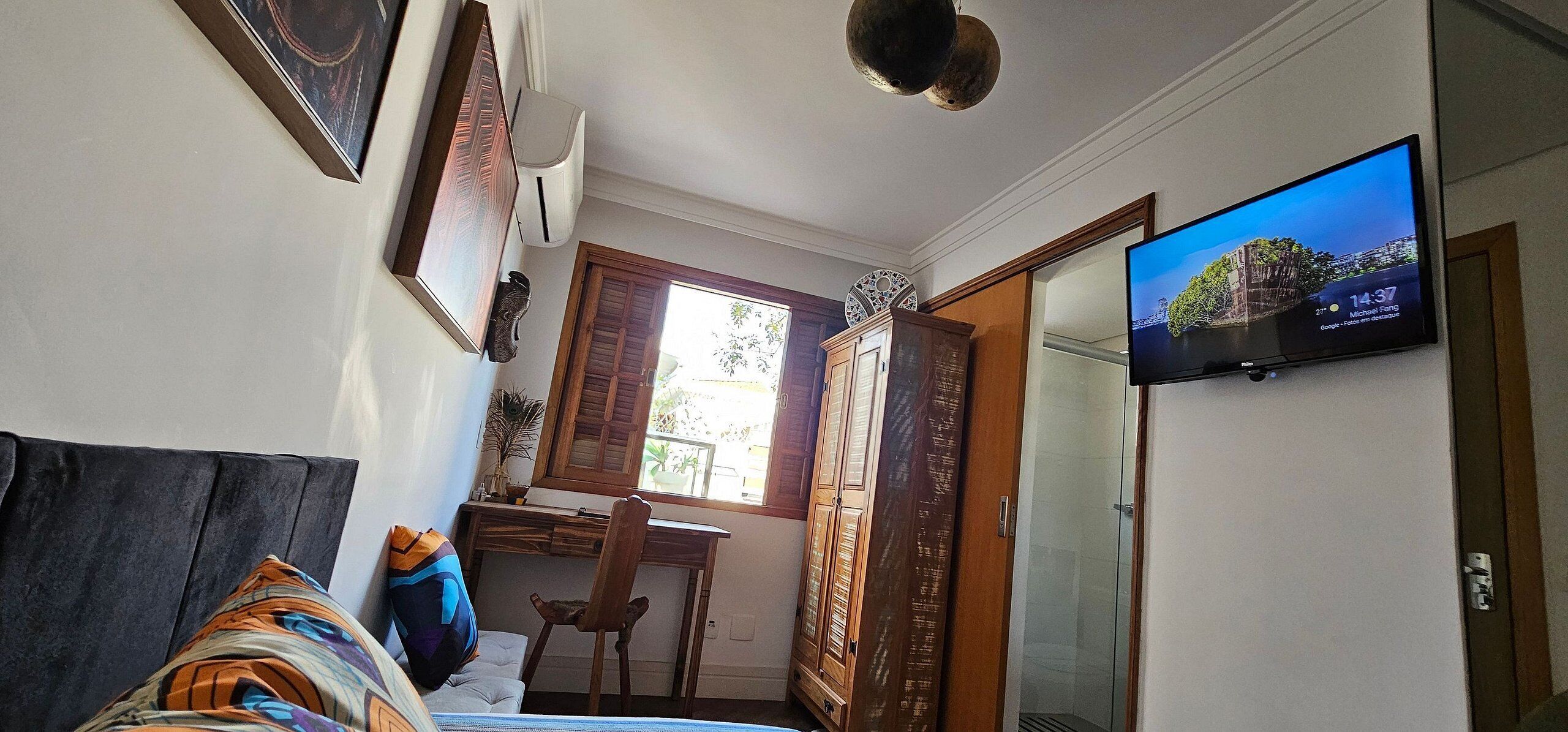 A bedroom with a bed, a desk, a chair, a TV, and a wardrobe.