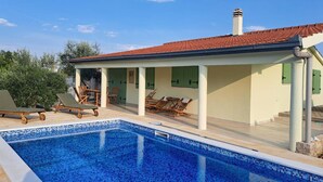 Une piscine avec des chaises longues et un patio couvert.