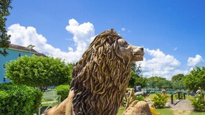 Une statue de lion dans un parc, avec des arbres et un ciel dégagé.