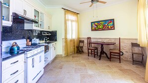 A kitchen with white cabinets, a stove, and a ceiling fan. - Oceanfront Apartment in Cabarete With Pool and Beach Access (Sosúa)