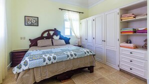 A bedroom with a bed, a wardrobe, and a window with curtains. - Oceanfront Apartment in Cabarete With Pool and Beach Access (Sosúa)