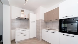 A modern kitchen with white cabinets, a black oven, and a stainless steel sink. - Beautiful apartment in Pridraga with WiFi (Pridraga)