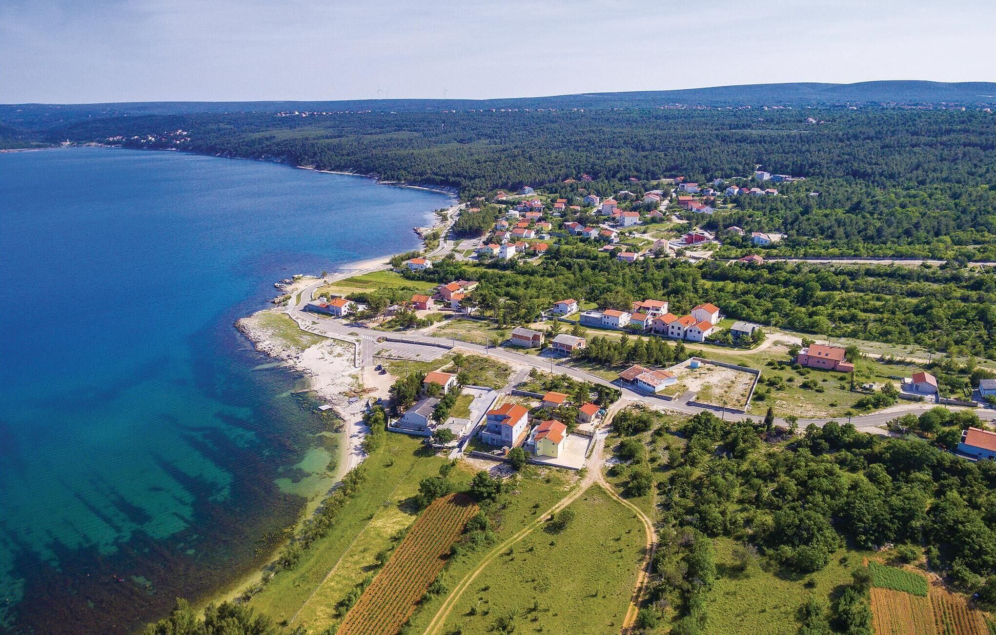 Vista aérea de un pueblo costero con casas, caminos y una playa.
