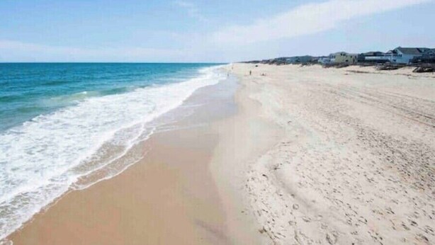 Une plage avec un rivage sablonneux et des vagues de l’océan.