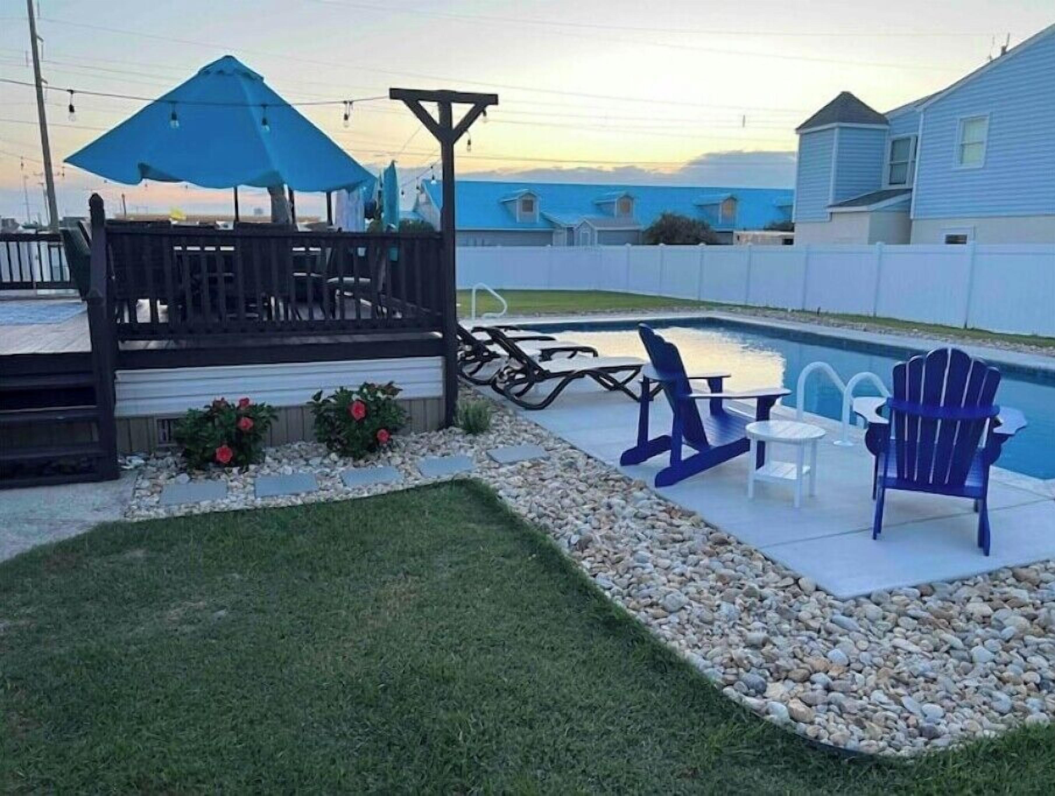 Ein Garten mit Pool, Terrasse und Gartenmöbeln.