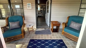 Une pièce chaleureuse avec deux fauteuils en osier, une petite table ronde et un tapis bleu à motifs.