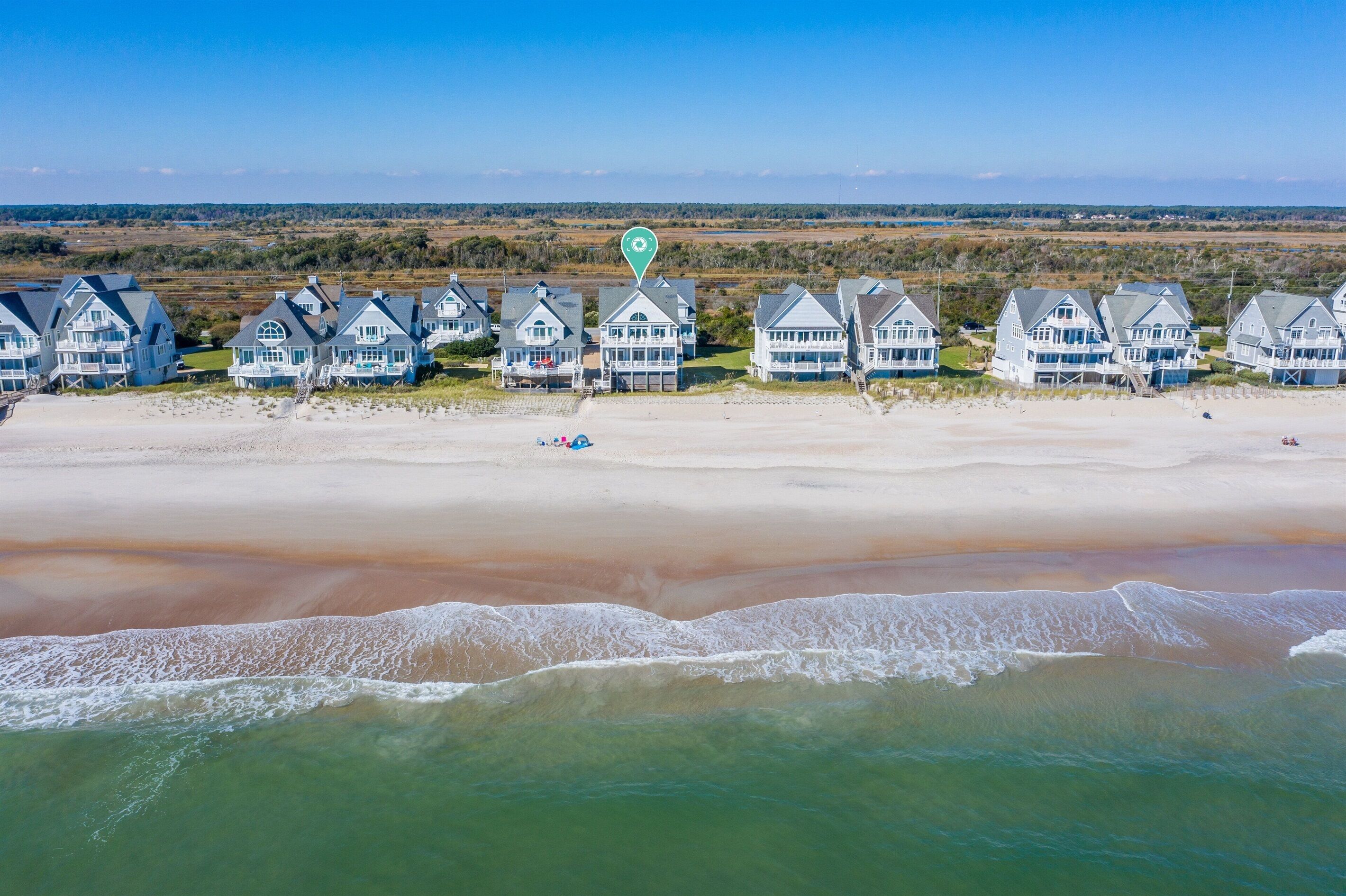 A beachfront property with multiple houses, a sandy beach, and ocean waves.
