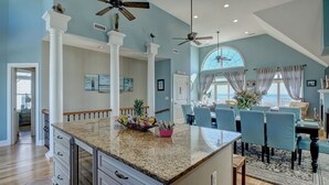 A spacious kitchen with granite countertops, white cabinetry, and a central island with fruit. - Oceanfront Paradise with Amazing Views! (North Topsail Beach)