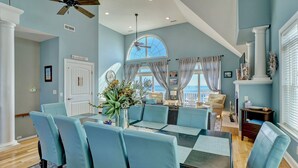 A dining area with a high ceiling, a large window, and a view of the outdoors. - Oceanfront Paradise with Amazing Views! (North Topsail Beach)
