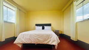 A hotel room with a bed, a nightstand, and a window with curtains.