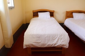 Two single beds with wooden headboards and white bedding in a room with a red carpet. - Casa Cóndor Ausangate (Ocongate)