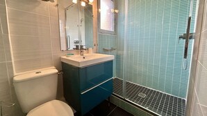 A bathroom with a toilet, sink, mirror, and shower. - Studio à Arcachon, emplacement idéal (ARCACHON)