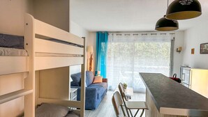 A compact room with bunk beds, a dining area, and a kitchenette. - Studio à Arcachon, emplacement idéal (ARCACHON)