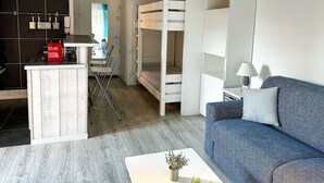 A compact living space with a kitchenette, a bunk bed, a sofa, and a dining area. - Studio à Arcachon, emplacement idéal (ARCACHON)