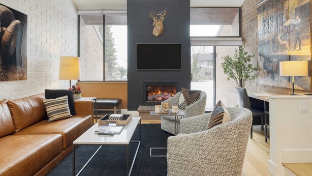 A modern living room with a fireplace, a mounted deer head, and a large painting on the wall.