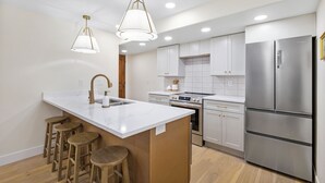 A modern kitchen with a central island, bar stools, stainless steel appliances, and pendant lighting. - Beautiful, New 2-bedroom Sundance Retreat (Orem)