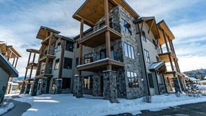 A multi-story building with a stone facade, balconies, and a wooden roof. - 1-bedroom + Den, Elk Creek Luxury Condo G301 (Fraser)