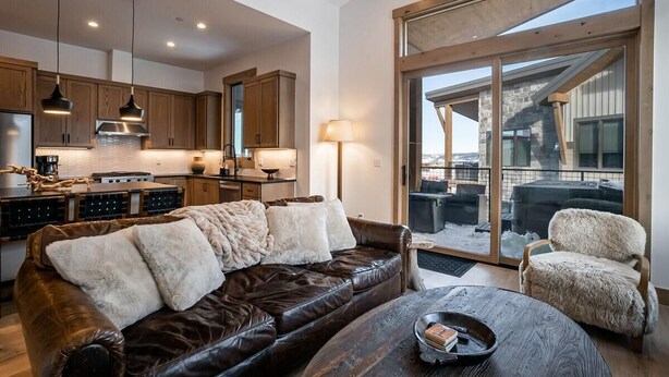 A spacious living area with a leather sofa, a coffee table, and a view of the outside. - 1-bedroom + Den, Elk Creek Luxury Condo G301 (Fraser)