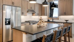 A modern kitchen with wooden cabinets, stainless steel appliances, a central island, and pendant lighting. - 1-bedroom + Den, Elk Creek Luxury Condo G301 (Fraser)