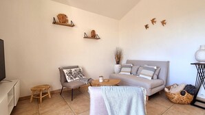 Una sala de estar acogedora con un sofá, un sillón, una mesita y un televisor sobre un mueble bajo.