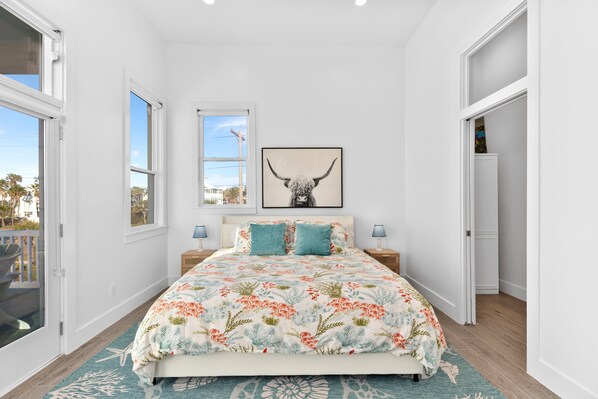 Un dormitorio con una cama, dos mesitas de noche, una ventana y una puerta.