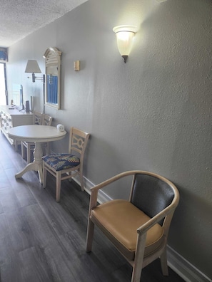Comedor con una mesa redonda, sillas, una lámpara y un aplique de pared.
