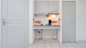 A kitchen with white cabinets, a countertop, and a coffee maker.