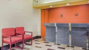 A reception area with a check-in counter, two red chairs, and a tiled floor. - OYO Budget Inn Bartow (Bartow)