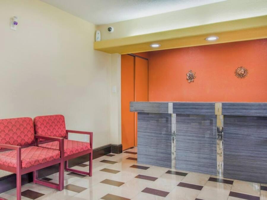 A reception area with a check-in counter, two red chairs, and a tiled floor.