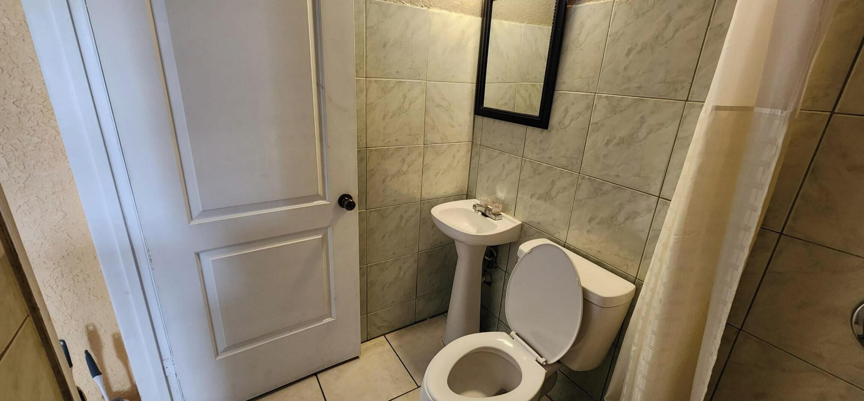 A small bathroom with a white toilet, a sink, and a mirror.