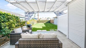 A covered patio with wicker furniture, a grill, and a well-maintained lawn. - 3 Bed Home, A/C, Parking, Big Yard in Heart of SD (San Diego)
