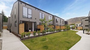 Un immeuble résidentiel moderne à plusieurs étages, doté d’un toit plat, de grandes fenêtres et d’une pelouse bien entretenue.