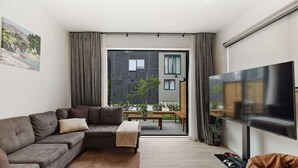 Un salon moderne avec un canapé gris, une table basse et un téléviseur à écran plat.