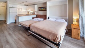 Een hotelkamer met twee bedden, een kitchenette en een badkamer.