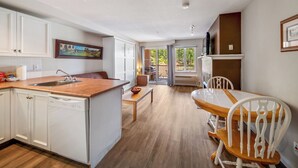 Een moderne keuken met witte kasten, een houten aanrecht en een eethoek met een houten tafel en stoelen.
