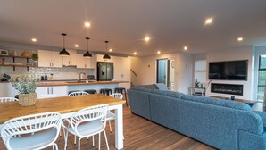 Een moderne keuken met witte kasten, een houten eettafel en hanglampen.