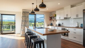 Een moderne keuken met een groot kookeiland, witte kastjes en uitzicht op bergen.
